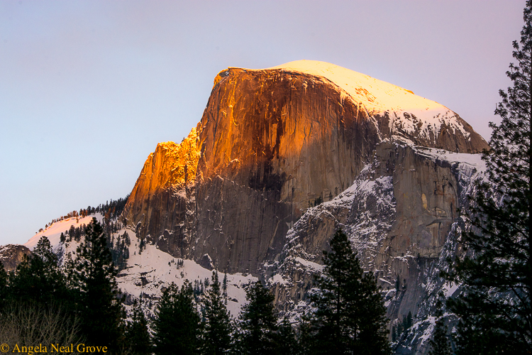 Image of Half Dome, Yosemite National Park in winter with a deep golden sunset glow on the top | Photo: Angela Neal Grove