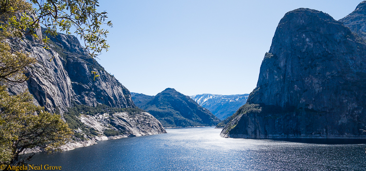 Image of Hetch Hetchy reservoir, Yosemite National Park. With snow capped mountains in background and Kolana Rock on right. | photo by Angela Neal Grove