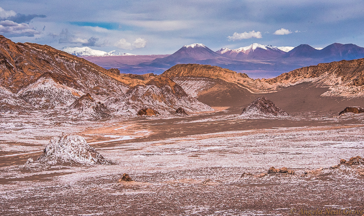 Otherworldly Atacama Desert.  Valley of Mars, Atacama has rugged rocky formations which give an other-worldly Mars-like look to this valley. The white frosting is salt. In the background is the chain of volcanoes on the border of Bolivia. PHOTO; ANGROVE