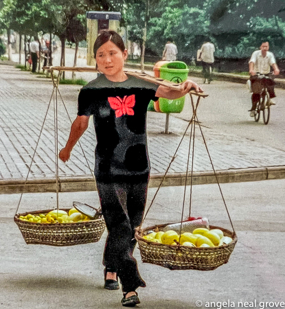 A woman carries fruit in pole baskets, Wuhan 2002.  There were very few cars, but some bicycles.PHOTO://ANGROVE