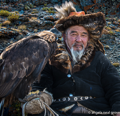 Eagle hunter in traditional dress rests with his eagle on  mountain in Western Mongolia
Photo:// ANGrove