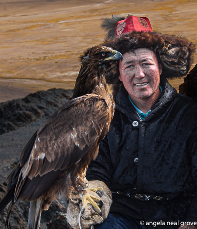 Eagle hunter in tradtional fur lined hat resting with his eagle on the Altai mountains in Western Mongolia.  Photo:// AN Grove