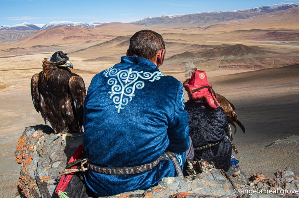 Two Kazakh eagle hunters with their eagles in the Altai Mountains of Western Mongolia looking down on the valley below.  Photo:// A.N.Grove