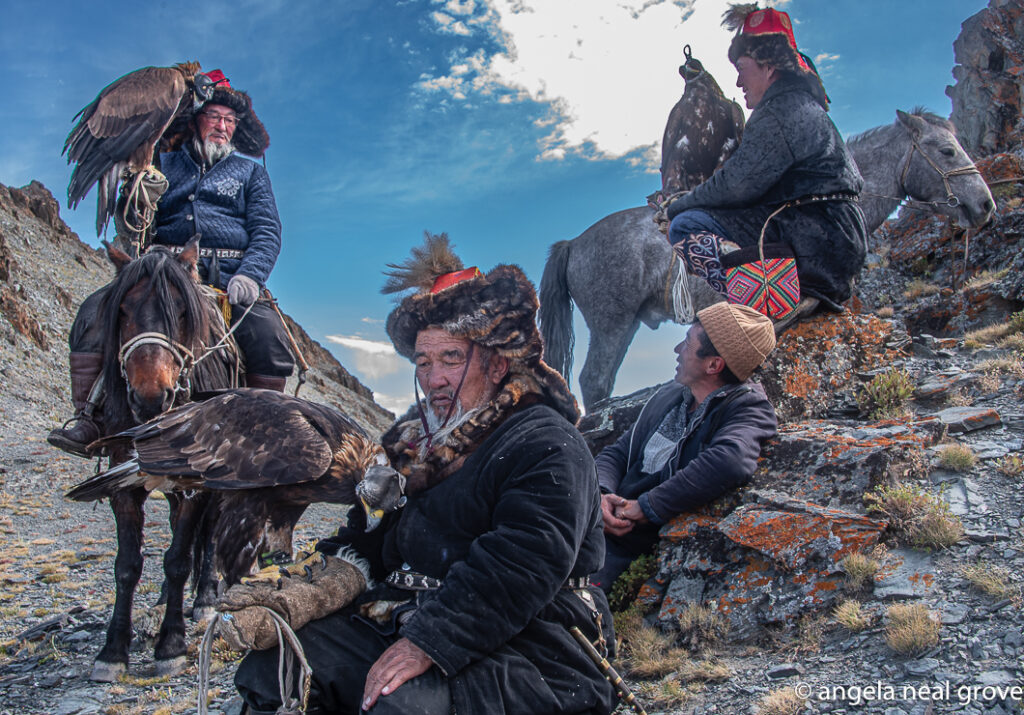 Altai mountains of Western Mongolia. Hunters, eagles and horses rest on the mountaintop after eagles hunted for fox. The thick sheepskin mitten the hunter wears protects his hands from eagle talons and is also a soft perch for the birds.
Photo:// A.N.Grove